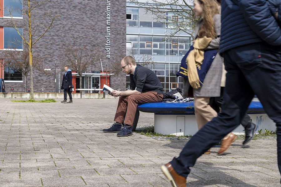 Student liest in einem Buch auf dem Campusplatz